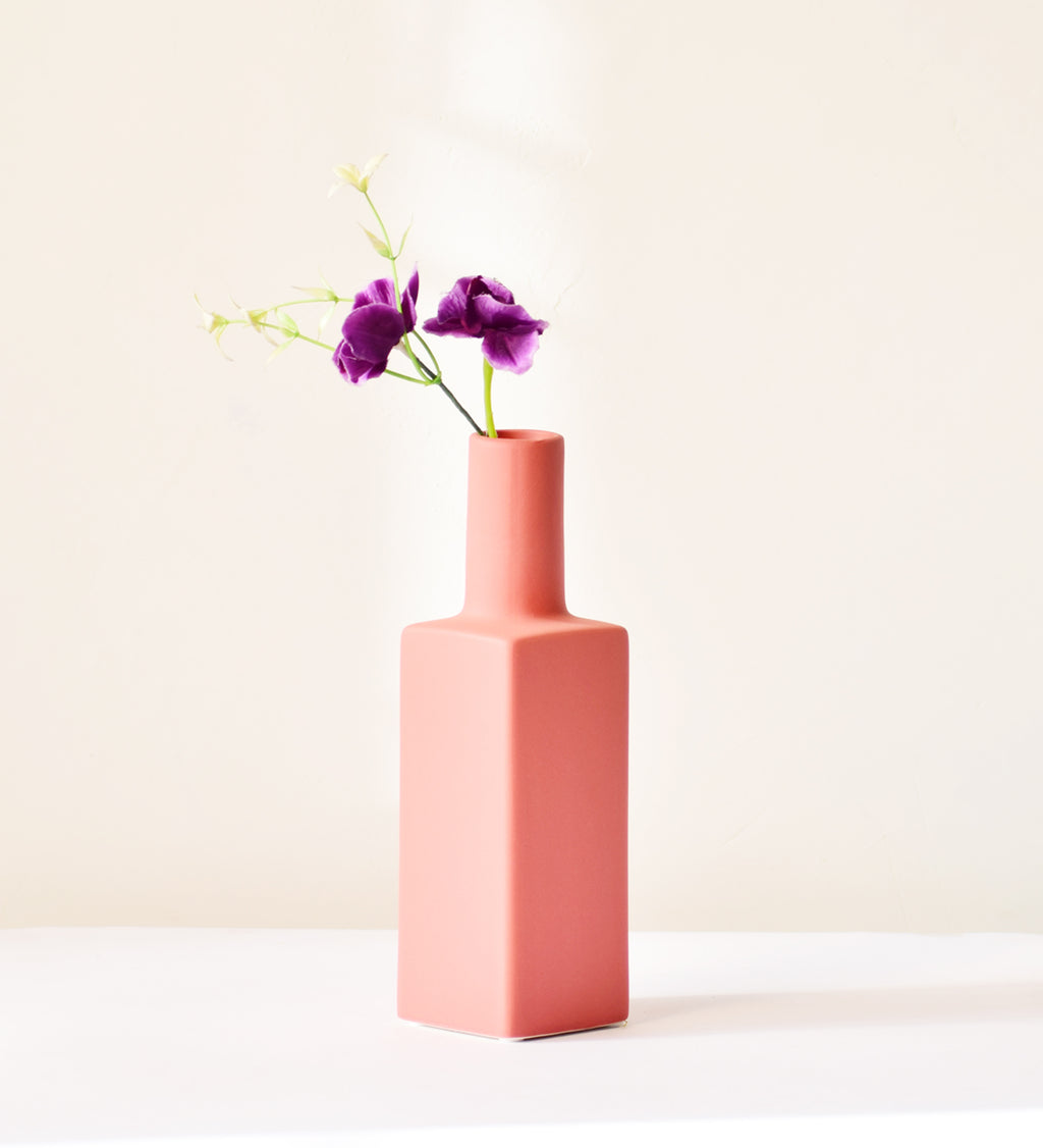 Luxury ceramic bottle-shaped vase with matte finish styled on a beige travertine console table in a modern Scandinavian-inspired interior with olive branches and minimalist décor.