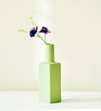 Luxury ceramic bottle-shaped vase with matte finish styled on a beige travertine console table in a modern Scandinavian-inspired interior with olive branches and minimalist décor.