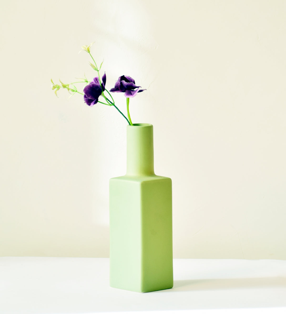 Luxury ceramic bottle-shaped vase with matte finish styled on a beige travertine console table in a modern Scandinavian-inspired interior with olive branches and minimalist décor.