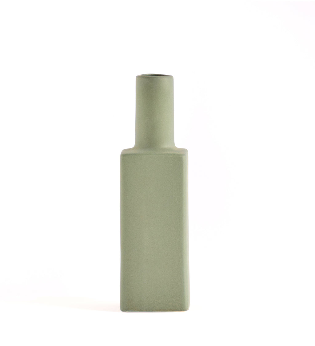 Luxury ceramic bottle-shaped vase with matte finish styled on a beige travertine console table in a modern Scandinavian-inspired interior with olive branches and minimalist décor.