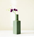 Luxury ceramic bottle-shaped vase with matte finish styled on a beige travertine console table in a modern Scandinavian-inspired interior with olive branches and minimalist décor.