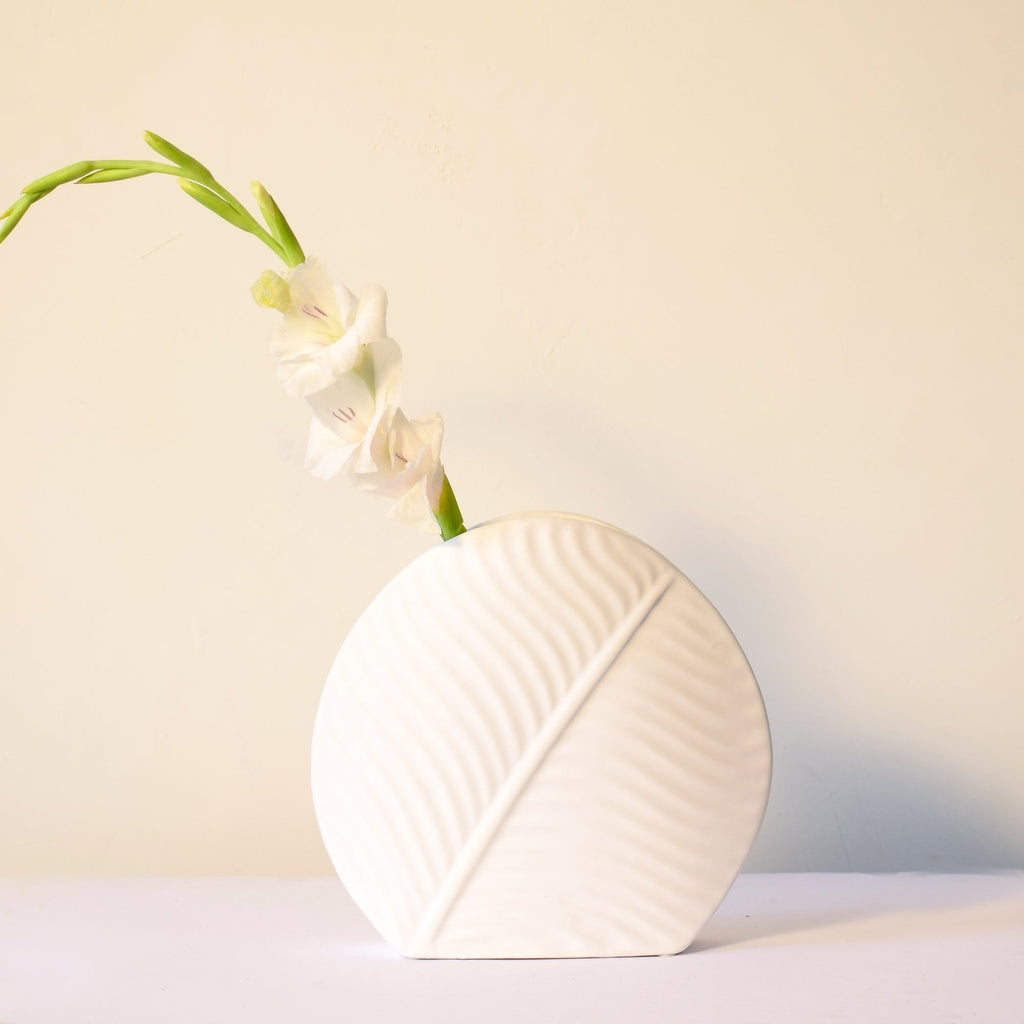 White leaf ceramic flower vase styled with fresh blooms in a modern luxury living room featuring elegant contemporary décor.

