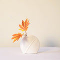White leaf ceramic flower vase styled with fresh blooms in a modern luxury living room featuring elegant contemporary décor.
