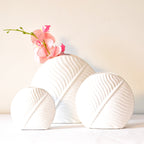 White leaf ceramic flower vase styled with fresh blooms in a modern luxury living room featuring elegant contemporary décor.
