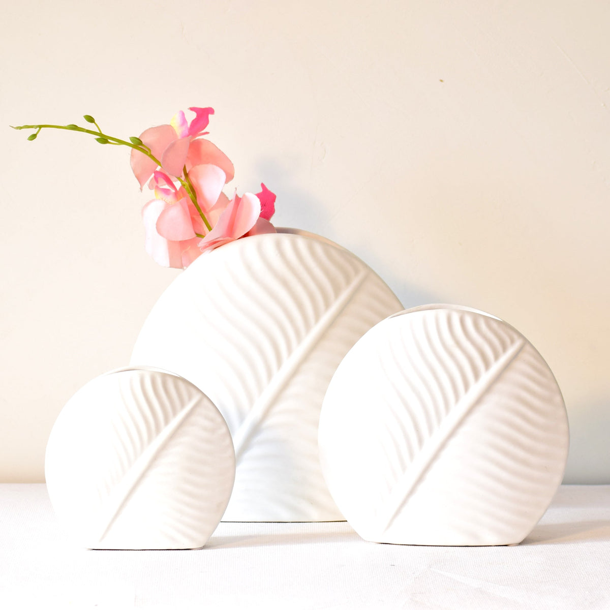 White leaf ceramic flower vase styled with fresh blooms in a modern luxury living room featuring elegant contemporary décor.
