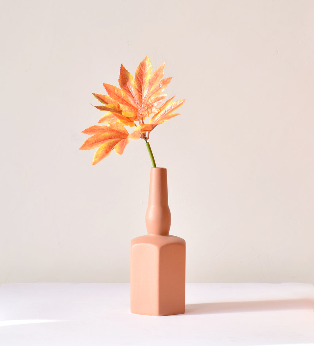 Luxury ceramic bottle-shaped vase with matte finish styled on a beige travertine console table in a modern Scandinavian-inspired interior with olive branches and minimalist décor.