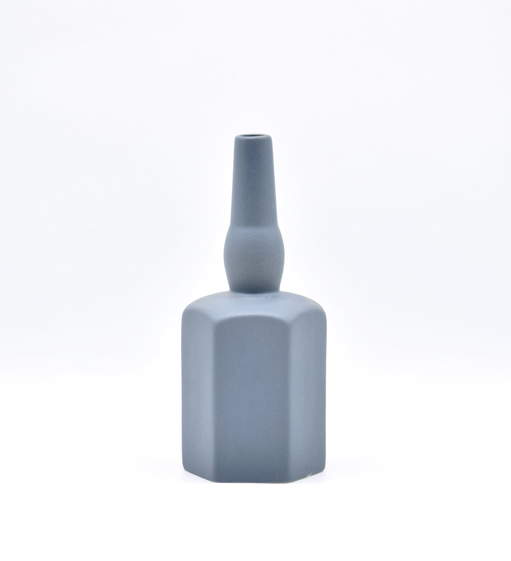 Luxury ceramic bottle-shaped vase with matte finish styled on a beige travertine console table in a modern Scandinavian-inspired interior with olive branches and minimalist décor.